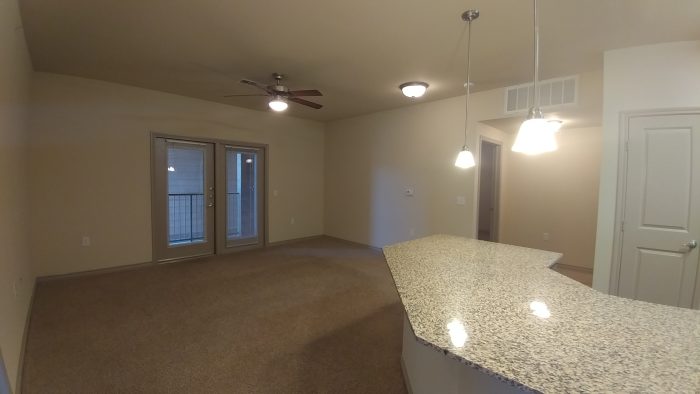 empty living room with granite counter tops and ceiling fan at The Anatole at City View