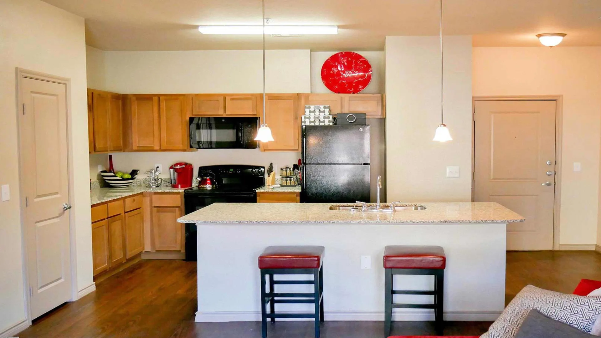 a kitchen with a refrigerator, stove, microwave and bar stools at The Anatole at City View